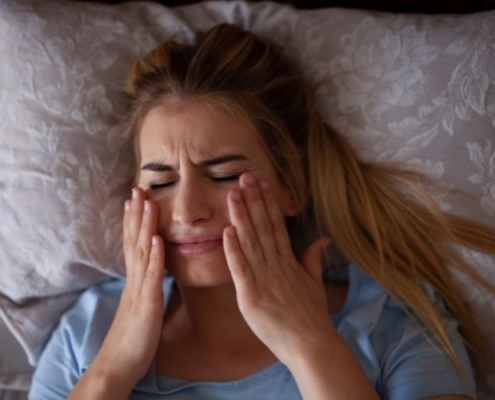 kobieta dotykająca swoich policzków z grymasem bólu